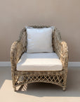 Wicker armchair with white cushions on a neutral background